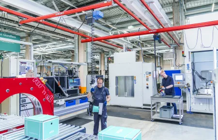 Demag KBK suspension cranes take care of the flat transport – here on a packaging line with a turning system.